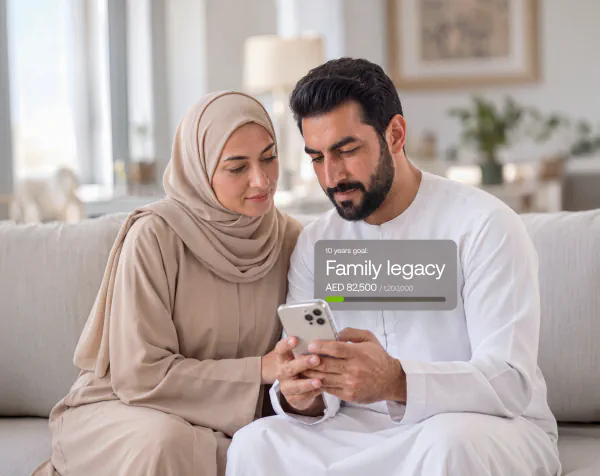 A couple reviewing their CUSP Wealth goal on a phone: 10 years goal, Family legacy, AED 82,500 of 1,200,000